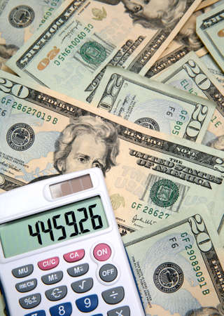 Lots of cash, twenty dollar bills, disperse over a table top and a calculator in vertical form.の写真素材