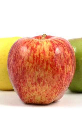 Red apple in front of a yellow and green apple, vertical format, white background.の写真素材