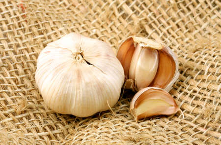 Garlics over a rustic fiber made of brown threads, centered in the photo.の写真素材