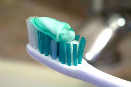 Bathroom view of a green toothbrush with green striped paste.