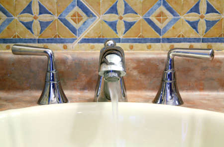 View of a faucet in a bathroom made of shiny metal.の写真素材