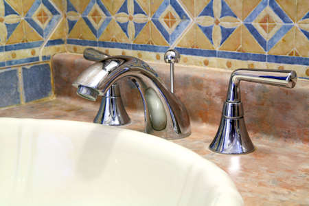 View of a faucet in a bathroom made of shiny metal.の写真素材