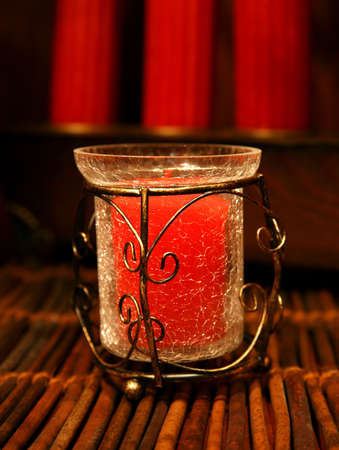Decorative Christmas candle in a vase over a wooden area with warm light.の写真素材
