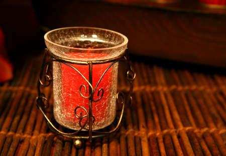 Decorative Christmas candle in a vase over a wooden area with warm light.の写真素材