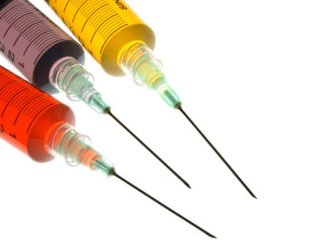 Back lighted image of a syringe containint colorful liquids for a high key effect.の写真素材