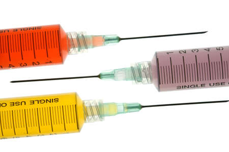 Back lighted image of a syringe containint colorful liquids for a high key effect.の写真素材