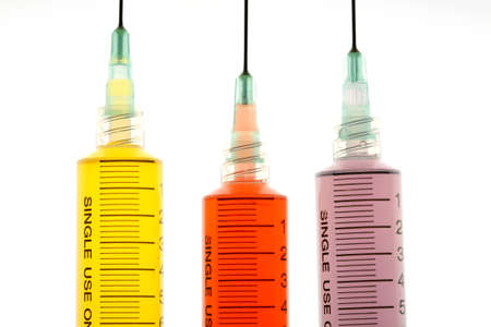 Back lighted image of a syringe containint colorful liquids for a high key effect.の写真素材