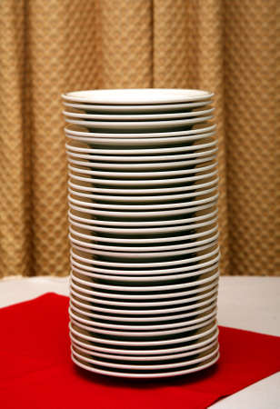 Stack of plates in a restaurant on a red table top.の写真素材