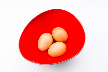 Eggs in red bowl with white backgroundの写真素材