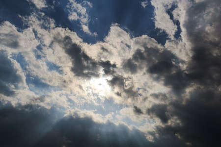 photo of the sky with the sun hidden by clouds and sun rays that filter
