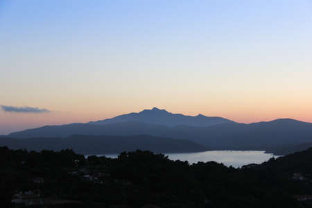 sunset over the hills, close to the sea with the sun hiddenの写真素材