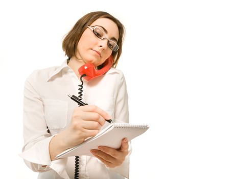 Young secretary making a note while holding a handsetの写真素材