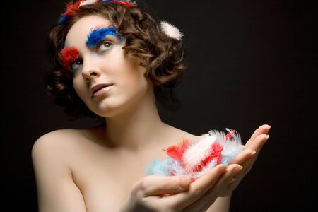 Beautiful girl holding colorful feathersの写真素材