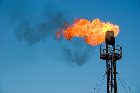 Burning oil flare on a blue skyの写真素材