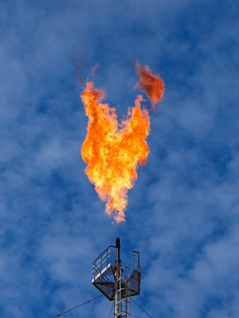 Burning oil gas flare over the blue skyの写真素材