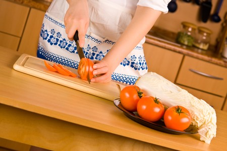 Woman's hands with knife cutting tomatoの写真素材