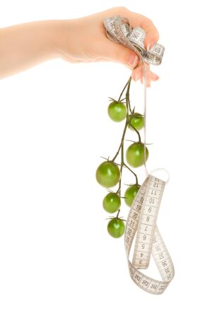 Woman's hands holding a twig with green tomatoes and measuring tapeの写真素材