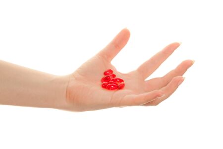 Woman's hand holding   red pills isolated on white