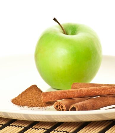 Picture of green apple and spices on the white plate (focus on cinnamon)の写真素材