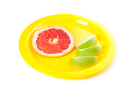 A picture of piece of grapefruit and apple on the yellow plateの写真素材