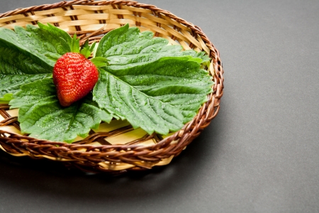 Red strawberry with leaves on the wooden plateの写真素材