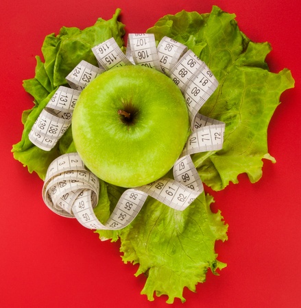 Picture of apple, lettuce  and tape measure on red backgroundの写真素材