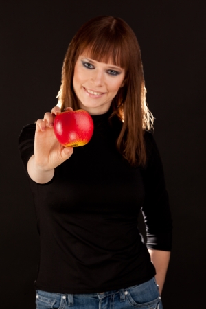 Beautiful woman with red apple smiling (focus on apple)の写真素材