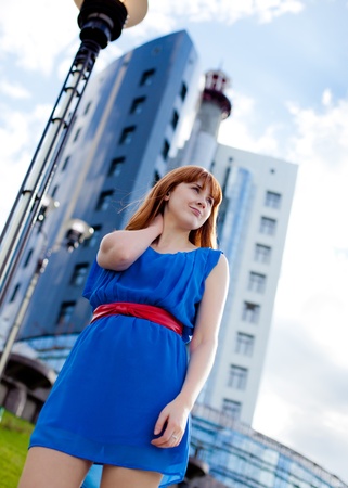 Beautiful ginger-haired woman in blue dress outdoorsの写真素材