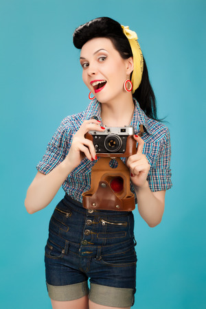 Retro pin-up woman with film camera on blue backgroundの写真素材