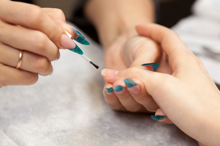 Beautician doing manicure with nail varnishの写真素材