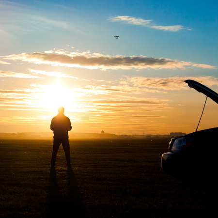 Picture of man silhouette with rc plane standing on sunsetの写真素材