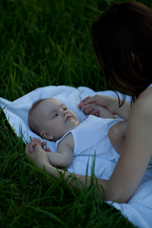 Happy woman with adorable baby lying on the grass. Happy beautiful family.の写真素材
