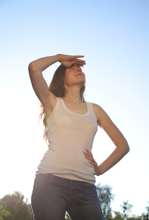 Beautiful woman standing against the sky and looking up. Sunny dayの写真素材
