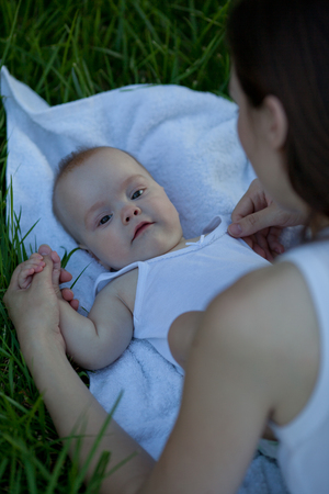 Woman with adorable baby lying on the grass. Happy beautiful family.の写真素材
