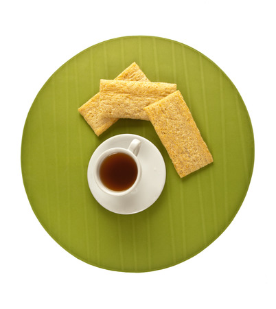 Picture of a cup of coffee and crisp bread on green plate isolated on whiteの写真素材