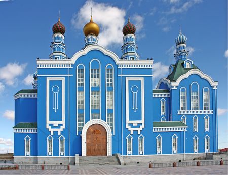 Blue church with striped domes under the cloudy skyの写真素材