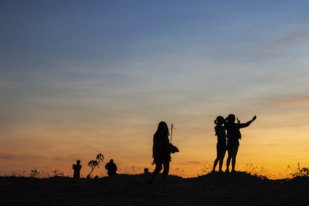 Silhouettes of lovers men and women stand on the background of sunset skyの写真素材
