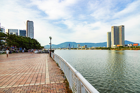 Da Nang, Vietnam - JUNE 23 , 2019: The Han River embankment. The empty cobblestone sidewalk with street lights, the handrail, trees and view of the city, river and distant mountains.のeditorial素材