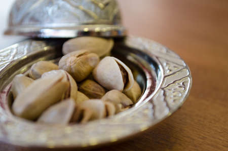 Copper bowl on a wooden table with pistachioの写真素材