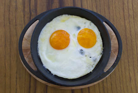 smiling happy face frying eggs breakfast with parsley in iron vintage pot on wooden table