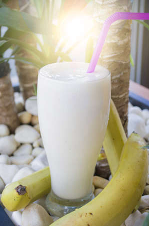 banana smoothie in a glass is placed on white stone backgroundの写真素材
