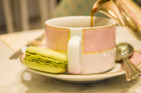 morning cup of coffee cake macaron and flower on light background from above beautiful breakfast