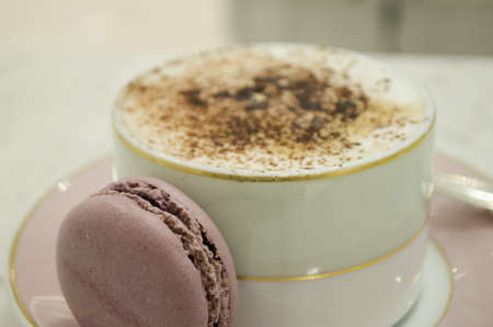 a cup of cappuccino and macaroons on a wooden table placeの写真素材