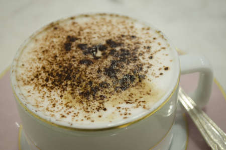 top view of hot coffee cappuccino latte art in white ceramic cup on wooden plate