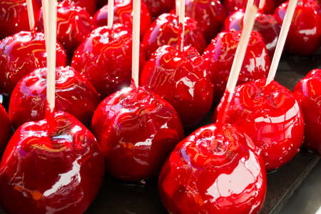 sweet glazed red toffee candy apples on sticks for sale on farmer market or country fairの写真素材