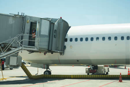 Modern passenger airplane parked to terminal building gate at airside apron of airport with airplane...