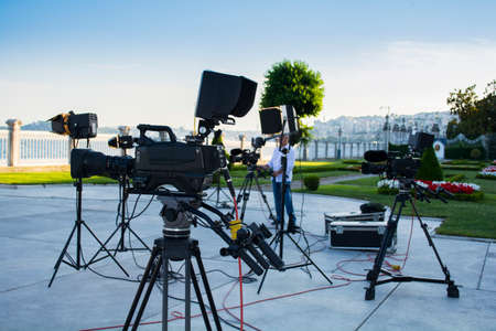 broadcast tv; movie shooting or video production and film, tv crew team with camera, light and audio equipment at outdoor locationの写真素材