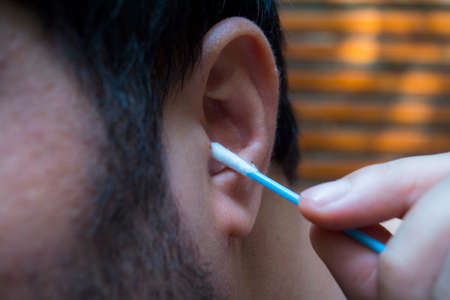 man cleaning ear with cotton budの写真素材