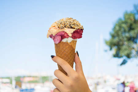 Female hand holding ice cream with chocolate sauce and cookies
