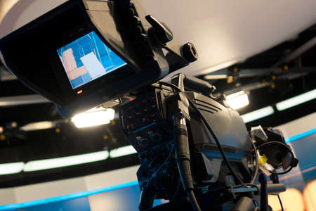 Television studio with camera and lights - recording TV show. Shallow depth of field - focus on cameraのeditorial素材